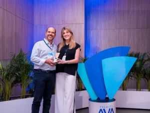 Un hombre y una mujer posando, juntos sostienen un trofeo de premios AVA.