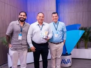 Tres hombres posando, el hombre del centro sostiene un premio AVA junto a los otros.